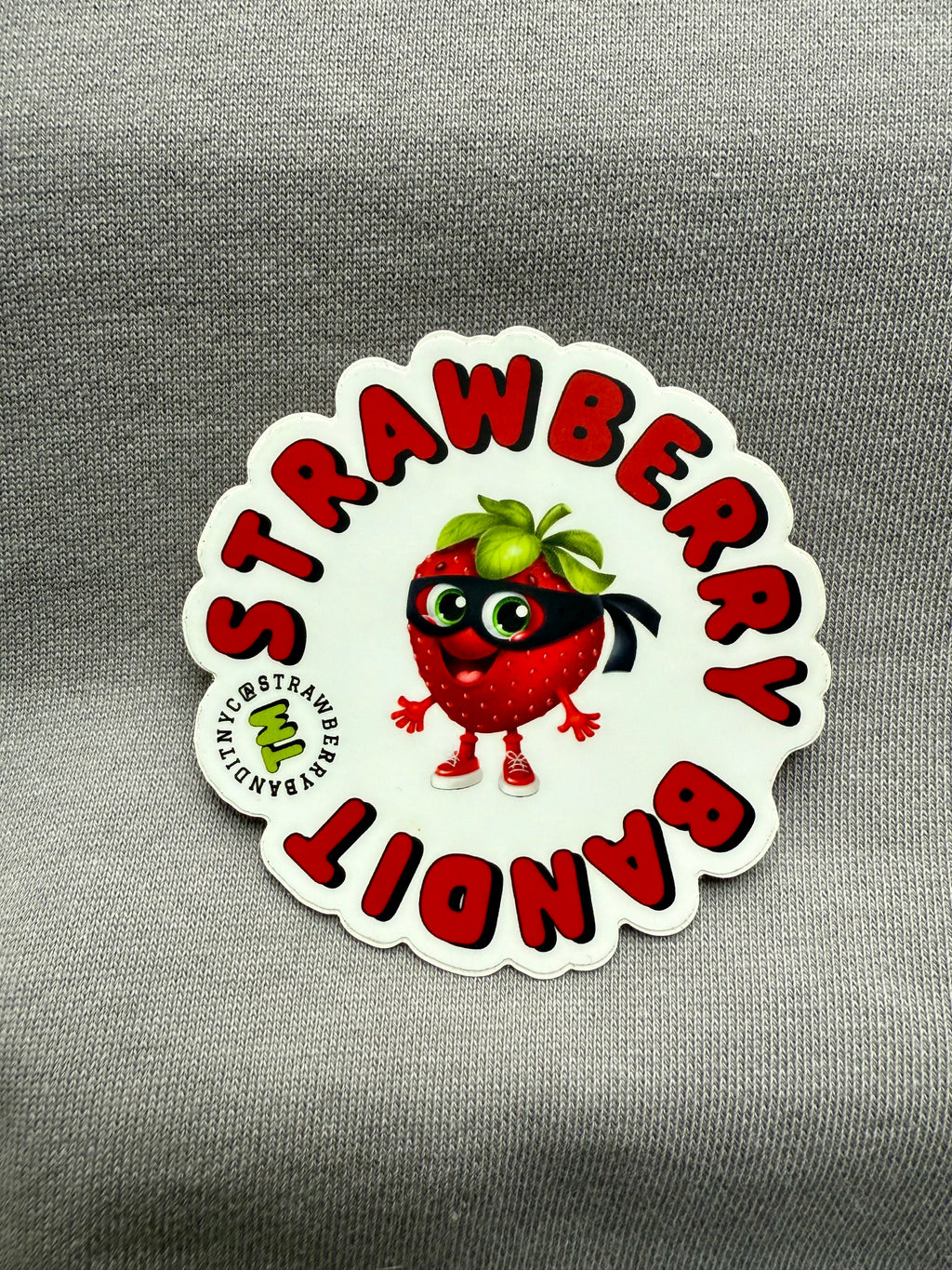Strawberry Bandit sticker featuring a playful strawberry character with a bandit mask and hat on a colorful background.