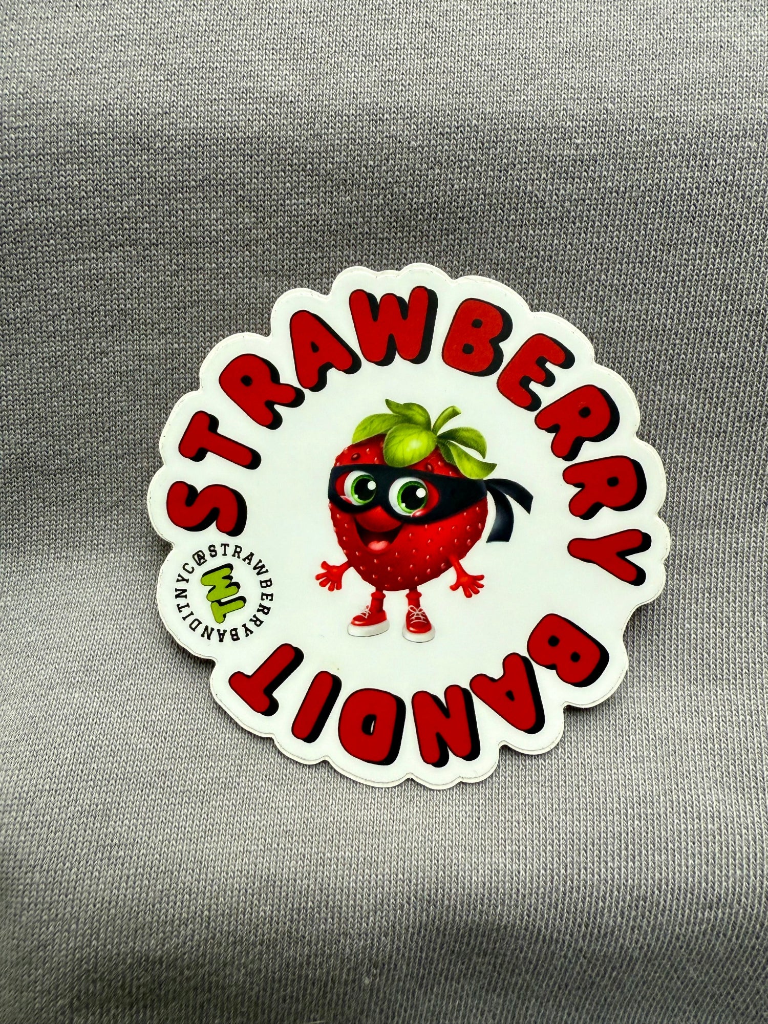 Strawberry Bandit sticker featuring a playful strawberry character with a bandit mask and hat on a colorful background.