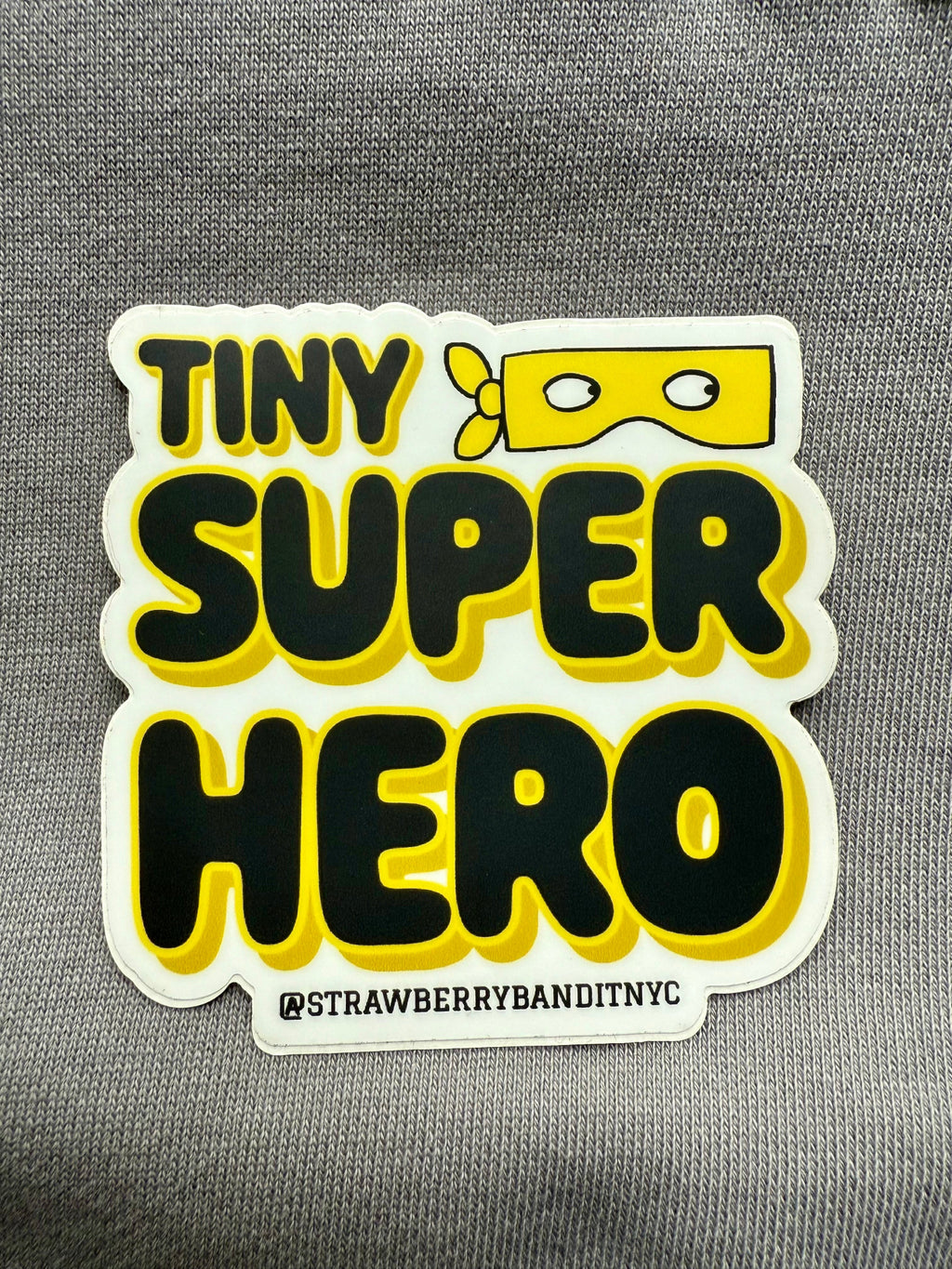 Colorful Tiny Superhero sticker by Strawberry Bandit featuring a small superhero character on a vibrant background.